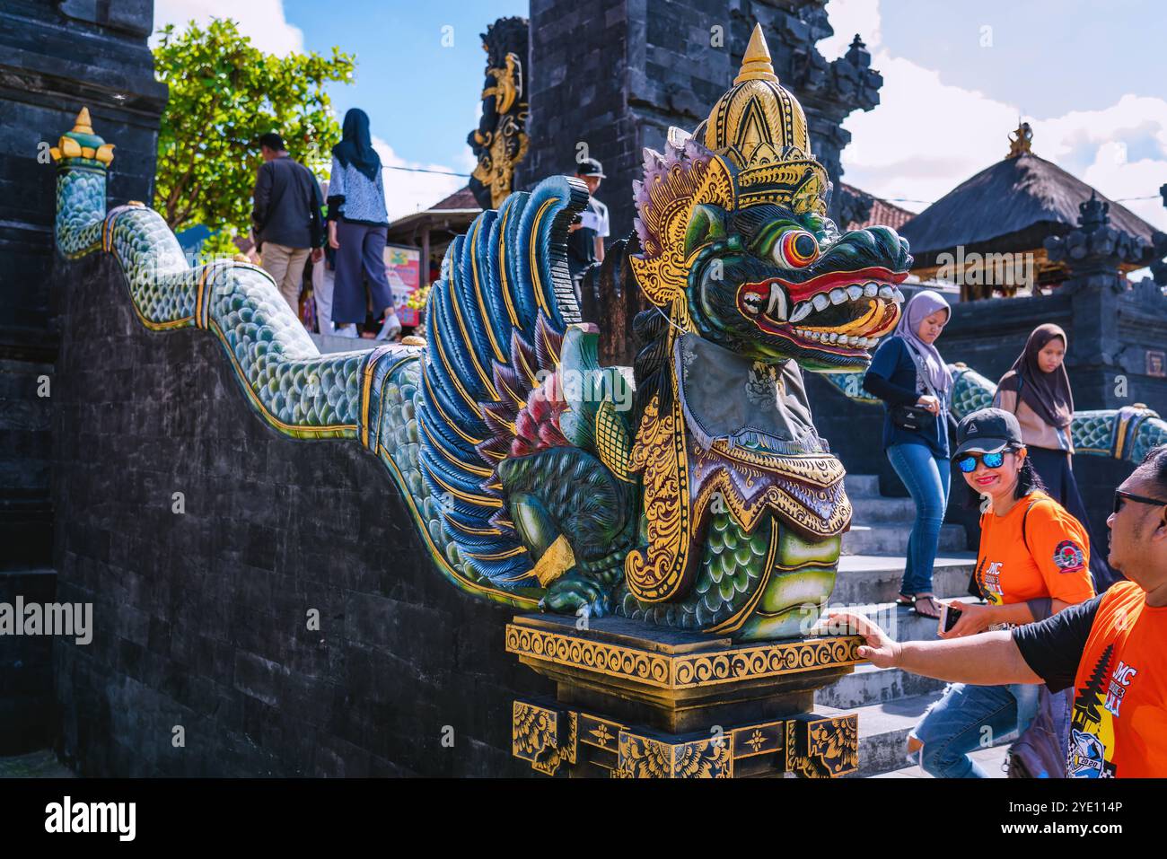 Touristes admirant la statue vibrante de Naga au temple Tanah Lot à Bali, Indonésie, par une journée ensoleillée. La sculpture colorée ajoute de la culture à ce monument populaire Banque D'Images