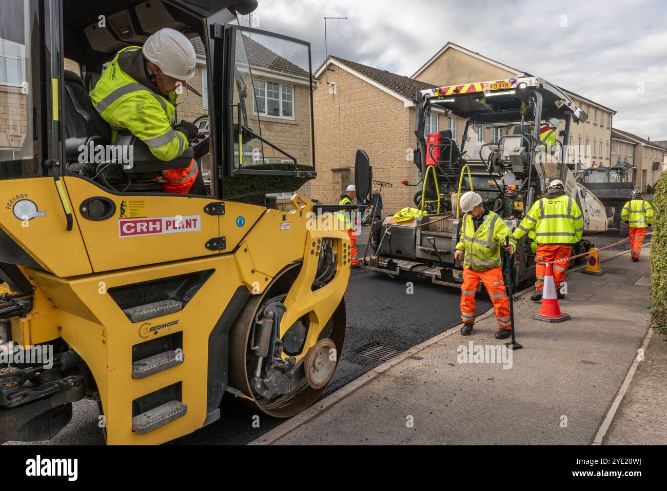 Une équipe d'ouvriers opérant de la machinerie lourde pour resurfaçer une route résidentielle dans le Wiltshire. Banque D'Images