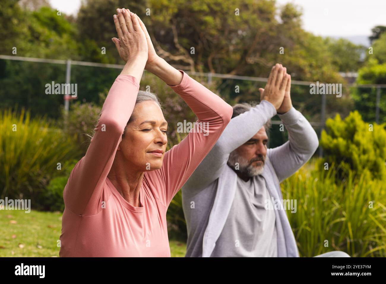 Pratiquer le yoga en plein air, couple mature méditant les yeux fermés, se sentant paisible Banque D'Images