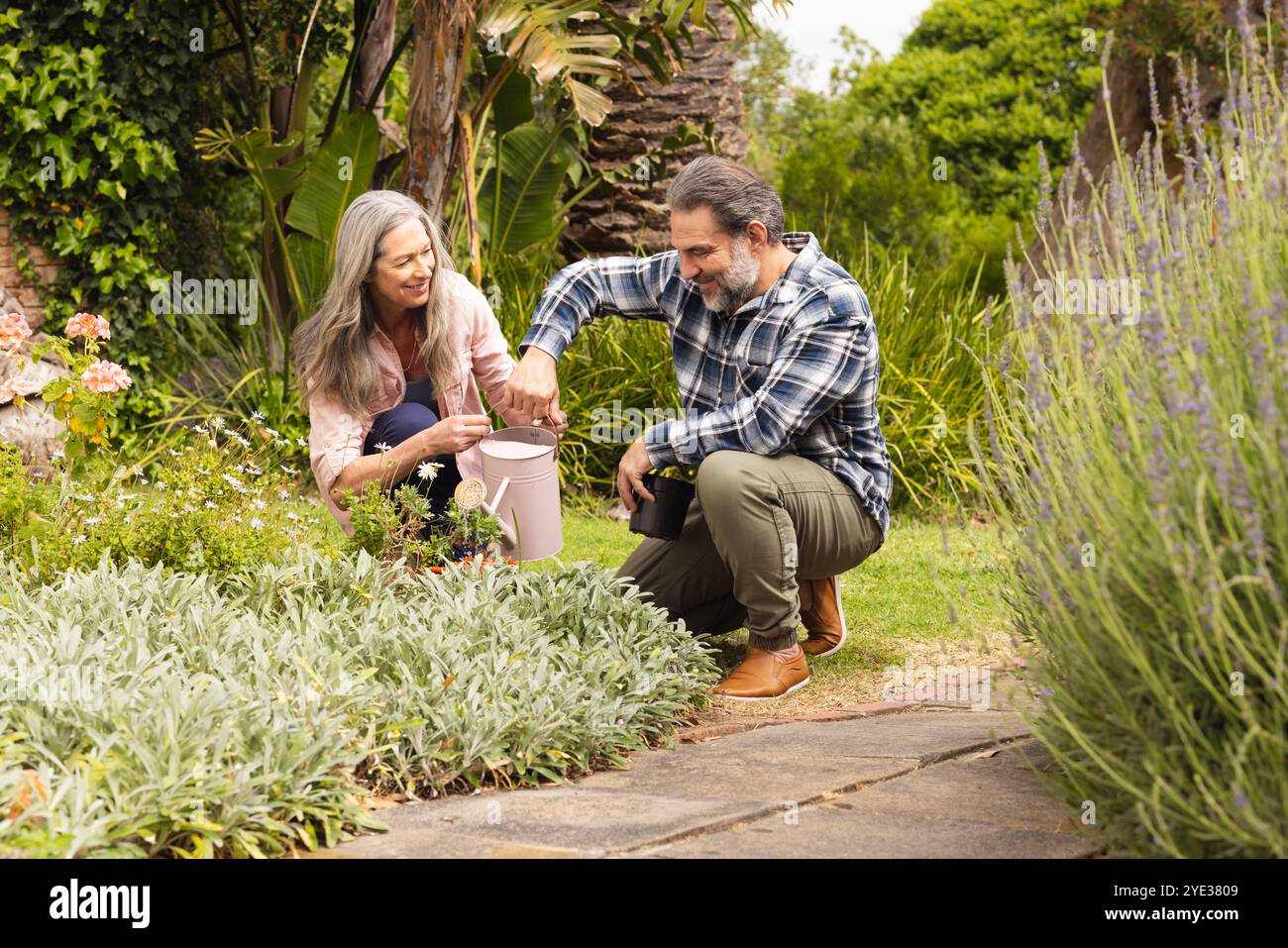 Couple mature jardinage ensemble, souriant et profitant du temps dans un jardin luxuriant, à l'extérieur Banque D'Images