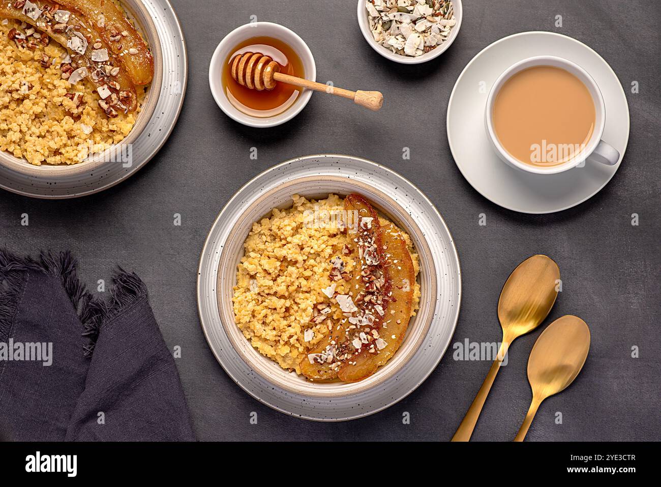 Photographie alimentaire de bouillie de millet avec banane caramélisée, noix de pécan, noix, flocons de noix de coco, chia, graines de lin, miel, thé au lait d'amande Banque D'Images