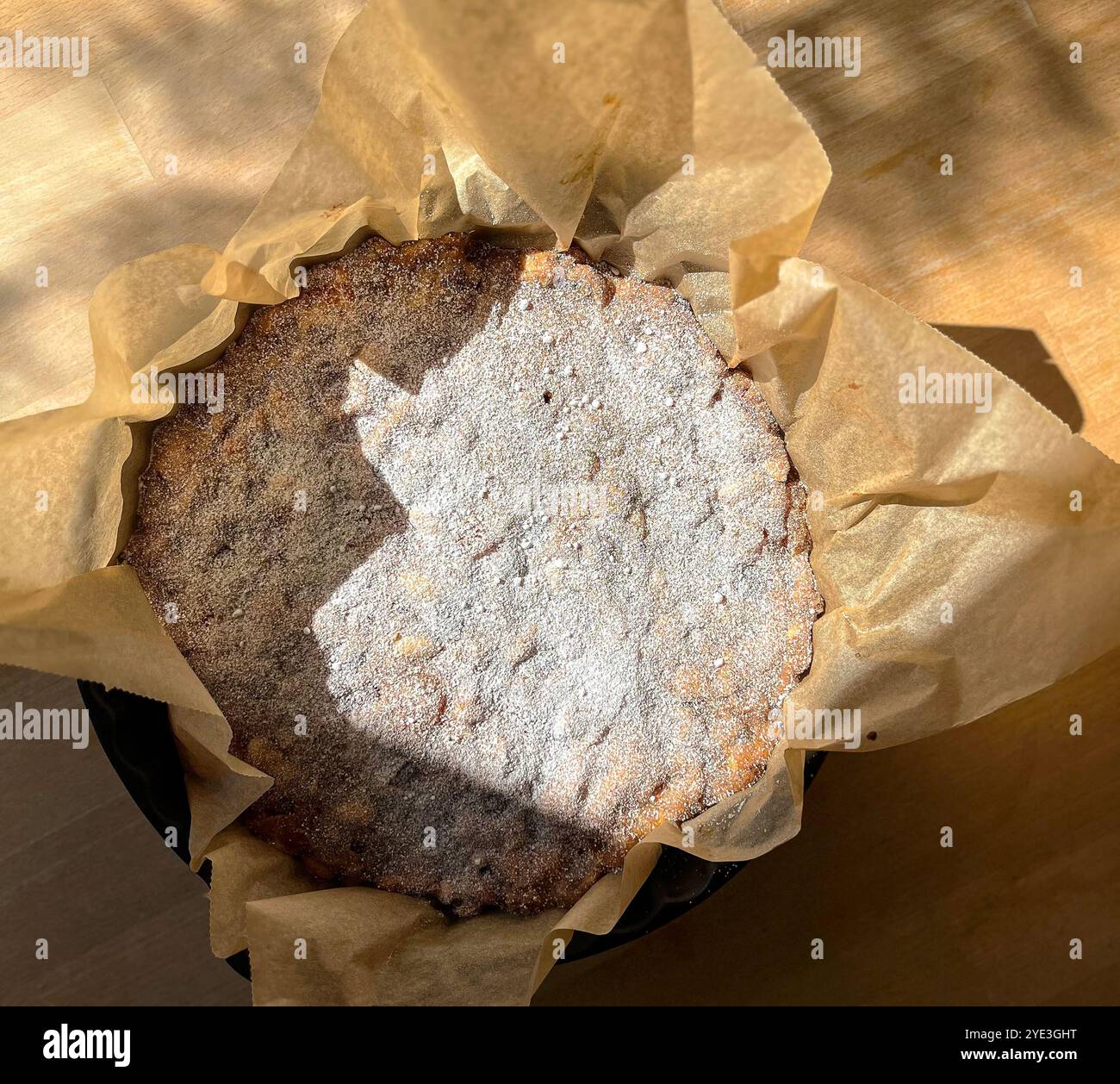 Photographie de nourriture de table d'un panforte dessert italien dans une forme de cuisson ronde en céramique noire avec du papier cuisson debout sur une table en bois Banque D'Images