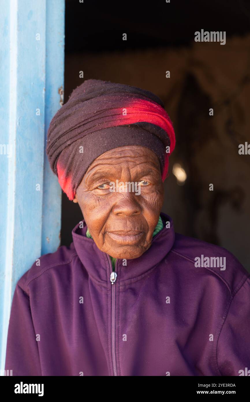 portrait de village d'une vieille femme africaine unique au visage froissé, debout devant une maison de boue dans le cadre de la porte Banque D'Images