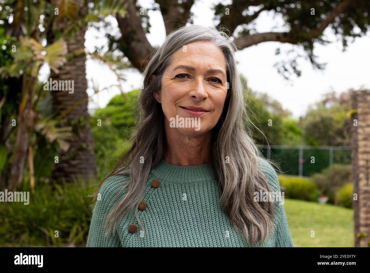 Femme mature souriante profitant d'un moment paisible en plein air dans un jardin luxuriant Banque D'Images