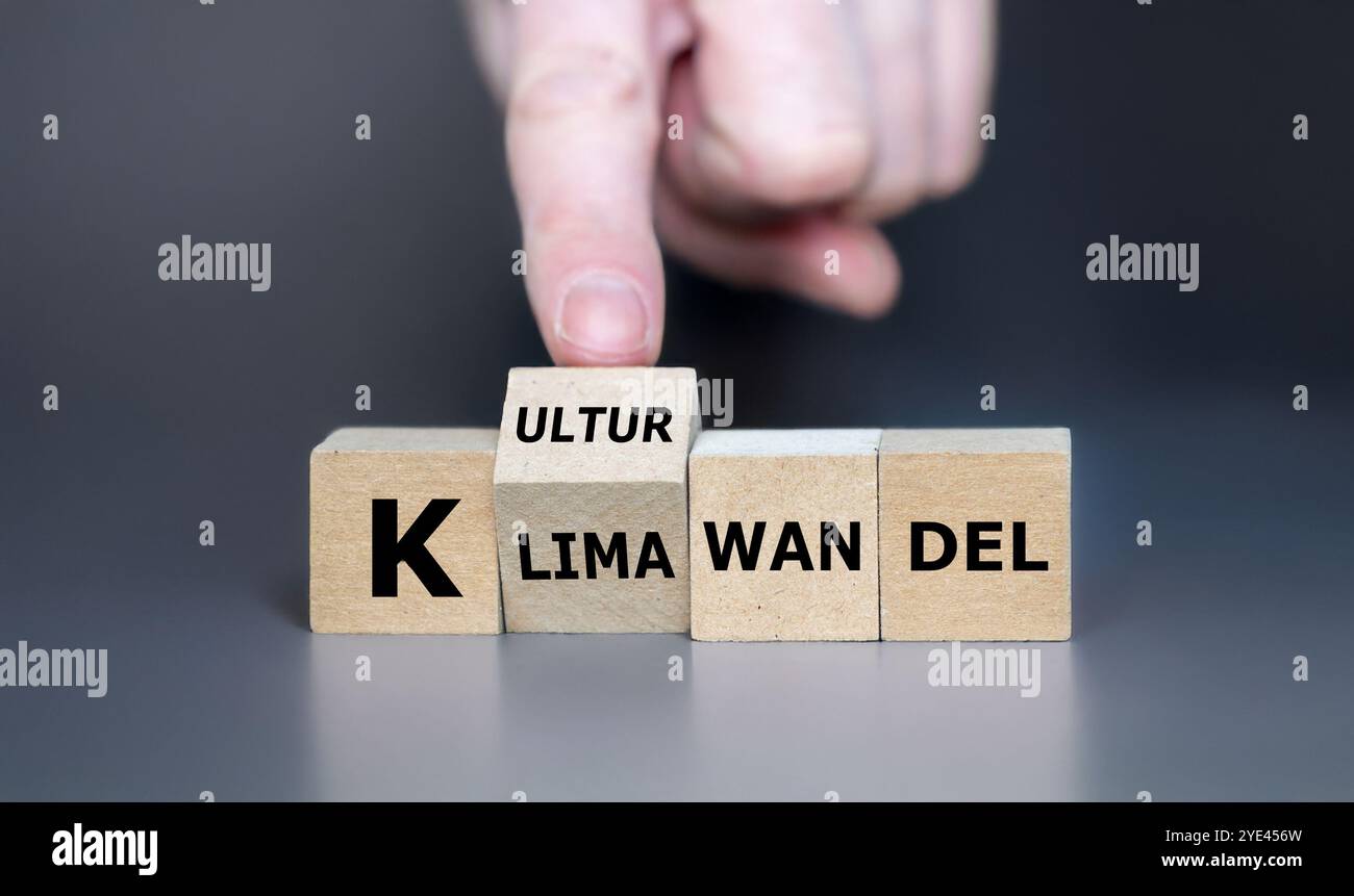 La main tourne le cube et change l'expression allemande 'Klimawandel' (changement climatique) en 'Kulturwandel' (changement de culture). Symbole indiquant que le changement climatique est réf Banque D'Images