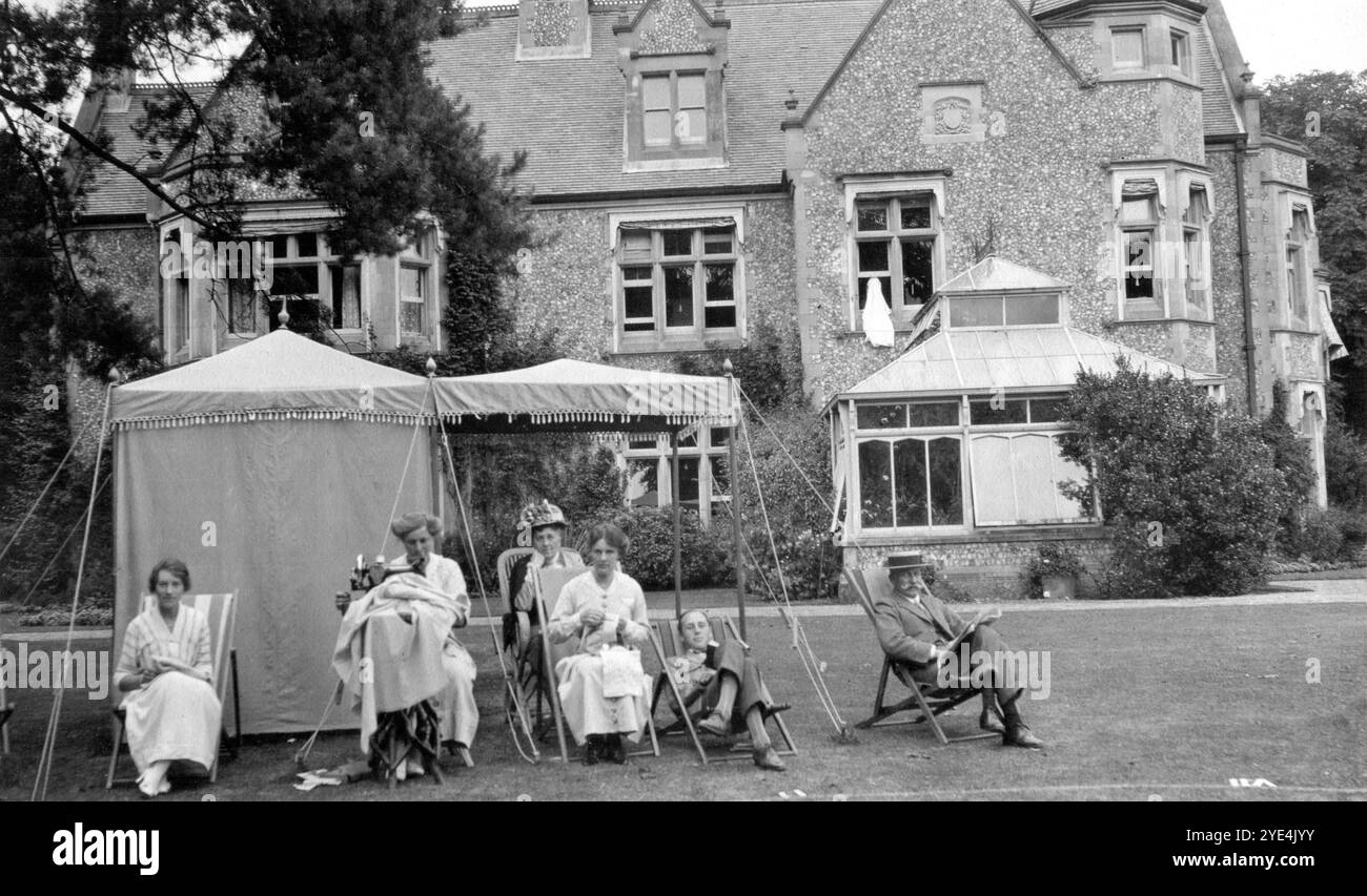 West Sussex, Angleterre. c.1913 – les membres de la famille Henty sont assis près d’une petite tente de pavillon sur la pelouse devant Ferring Grange, à Ferring, un village côtier de West Sussex. Ce domaine était la maison d'Edwin Henty, J. P, D.L., F.S.A. (1844-1916), qui avait servi comme haut shérif du Sussex. En 1924, la maison a été convertie en un hôtel à la mode, visité par de nombreuses célébrités dont Edward, le prince de Galles (plus tard connu sous le nom de duc de Windsor). La maison a été détruite par un incendie en octobre 1946. Banque D'Images