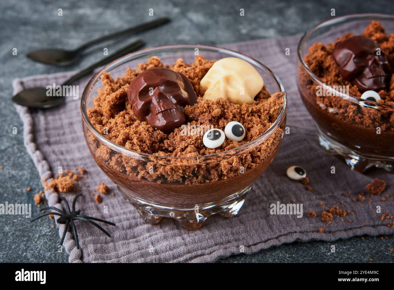 Halloween Party chocolat puddings ou Panna Cotta avec des crumbles de brownie et des sculls de chocolat servis dans un verre clair sur fond gris foncé. Idée de fête Banque D'Images