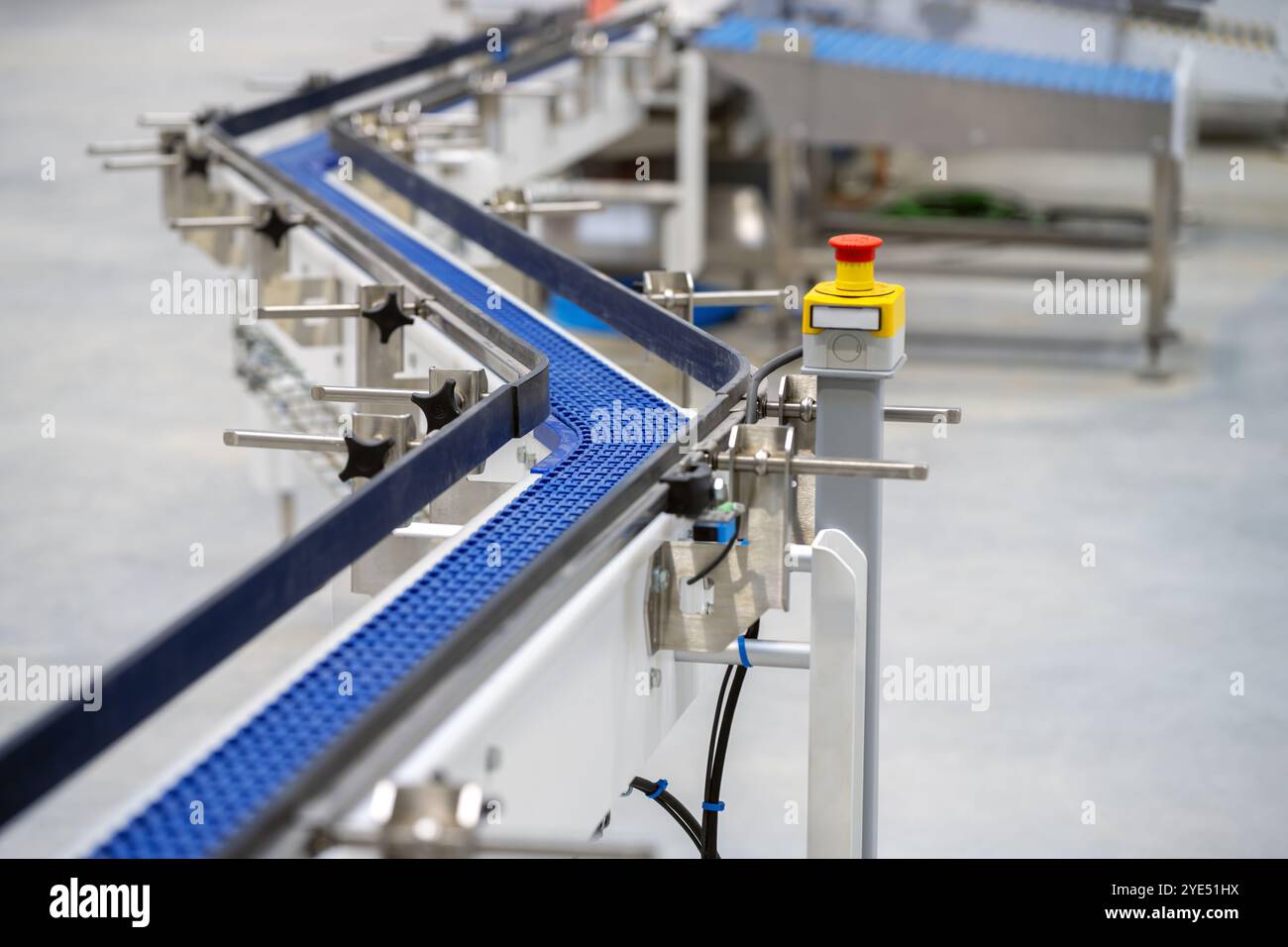 Convoyeur à chaîne en forme de zet en plastique hygiénique et bouton d'urgence photographie rapprochée dans une usine de fabrication alimentaire Banque D'Images