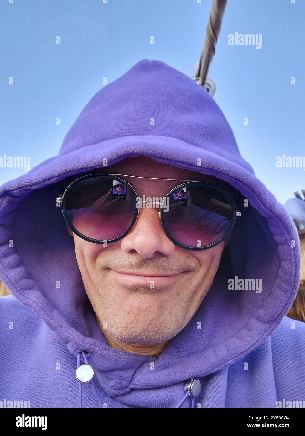 homme souriant avec sweat à capuche violet et lunettes de soleil, portrait Banque D'Images