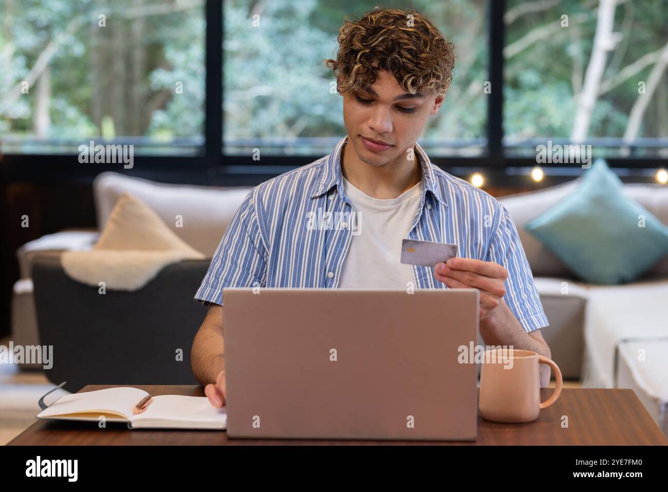 Temps de Noël, à la maison, jeune homme utilisant un ordinateur portable et une carte de crédit pour les achats en ligne Banque D'Images