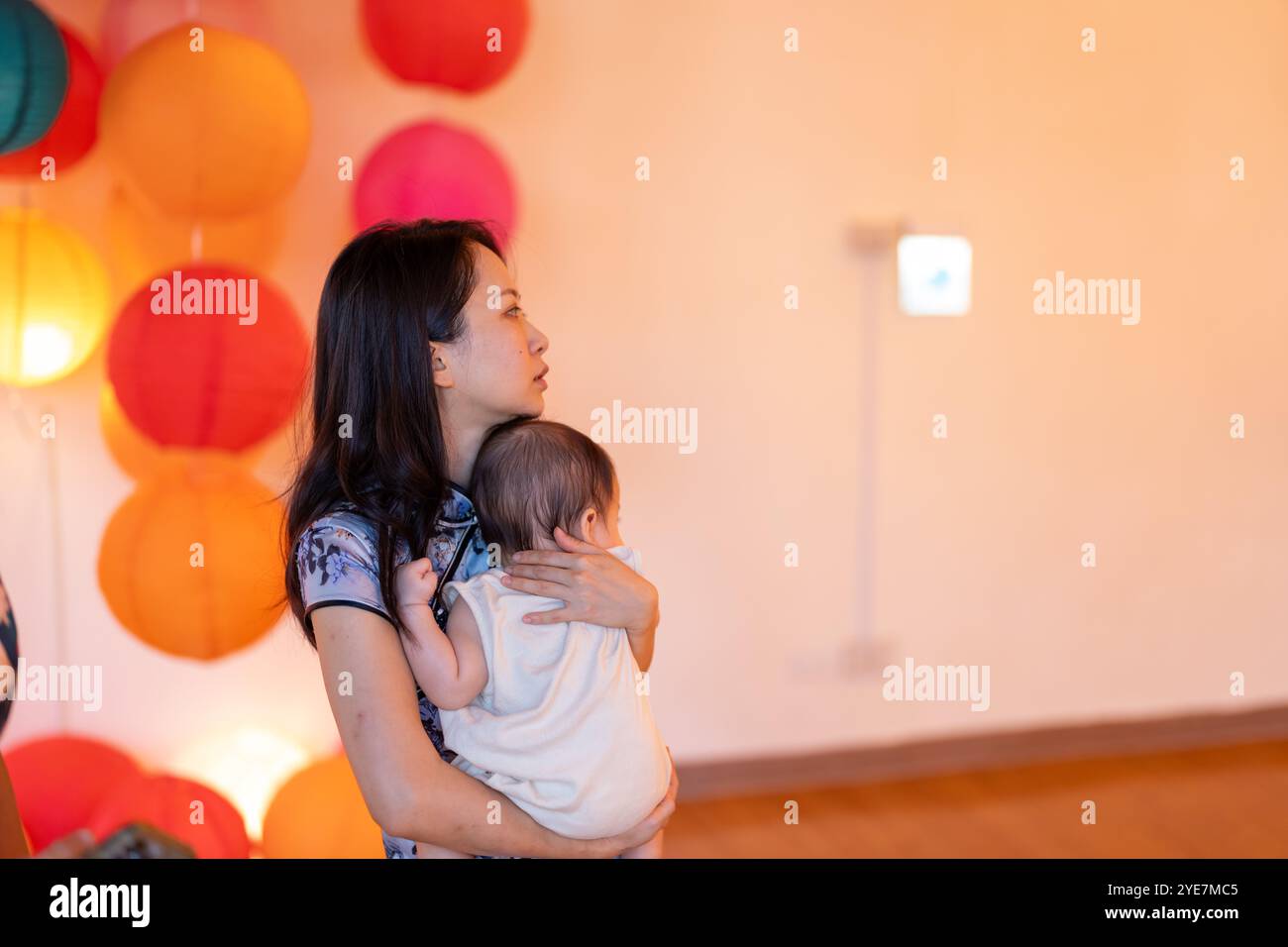 Une femme de 30 ans portant des vêtements traditionnels chinois tient son bébé de 6 mois dans un endroit coloré et accueillant pour la photo à Taipei, Taiwan, en septembre. Banque D'Images