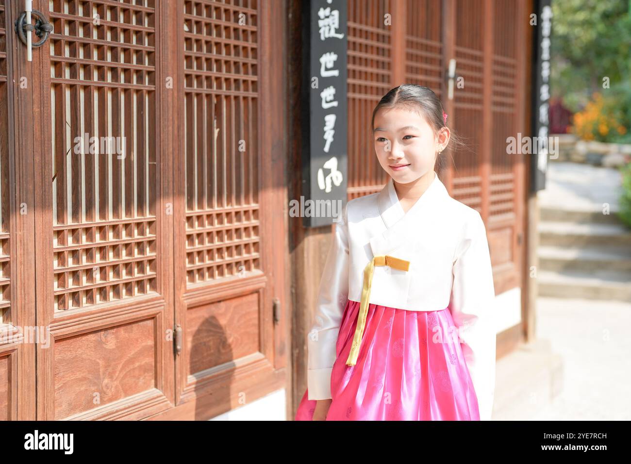Une jeune coréenne de 9 ans portant un hanbok se tient debout devant un bâtiment traditionnel dans la ville historique de Gyedong-gil, district de Jongno, Séoul. Banque D'Images