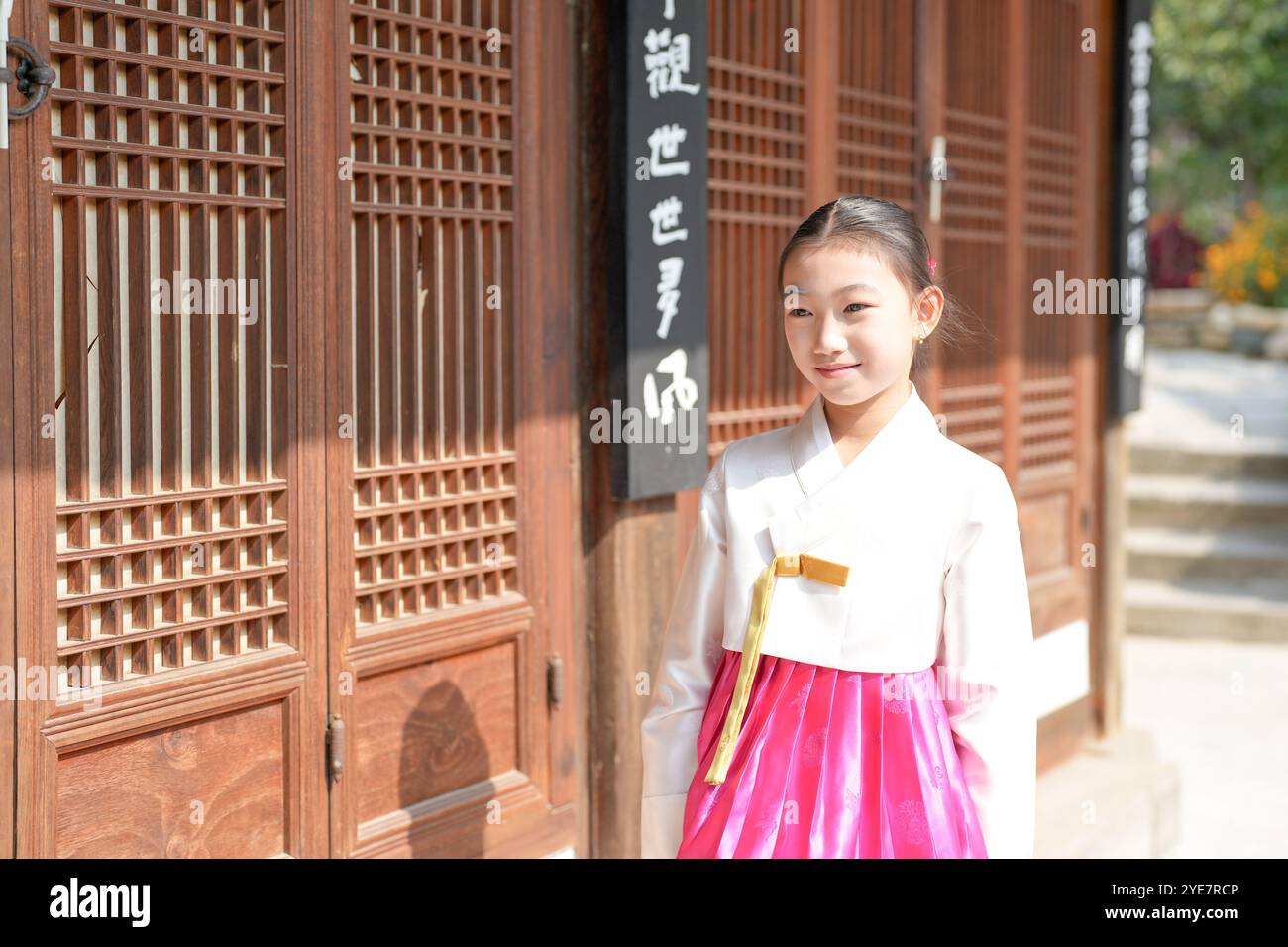 Une jeune coréenne de 9 ans portant un hanbok se tient debout devant un bâtiment traditionnel dans la ville historique de Gyedong-gil, district de Jongno, Séoul. Banque D'Images