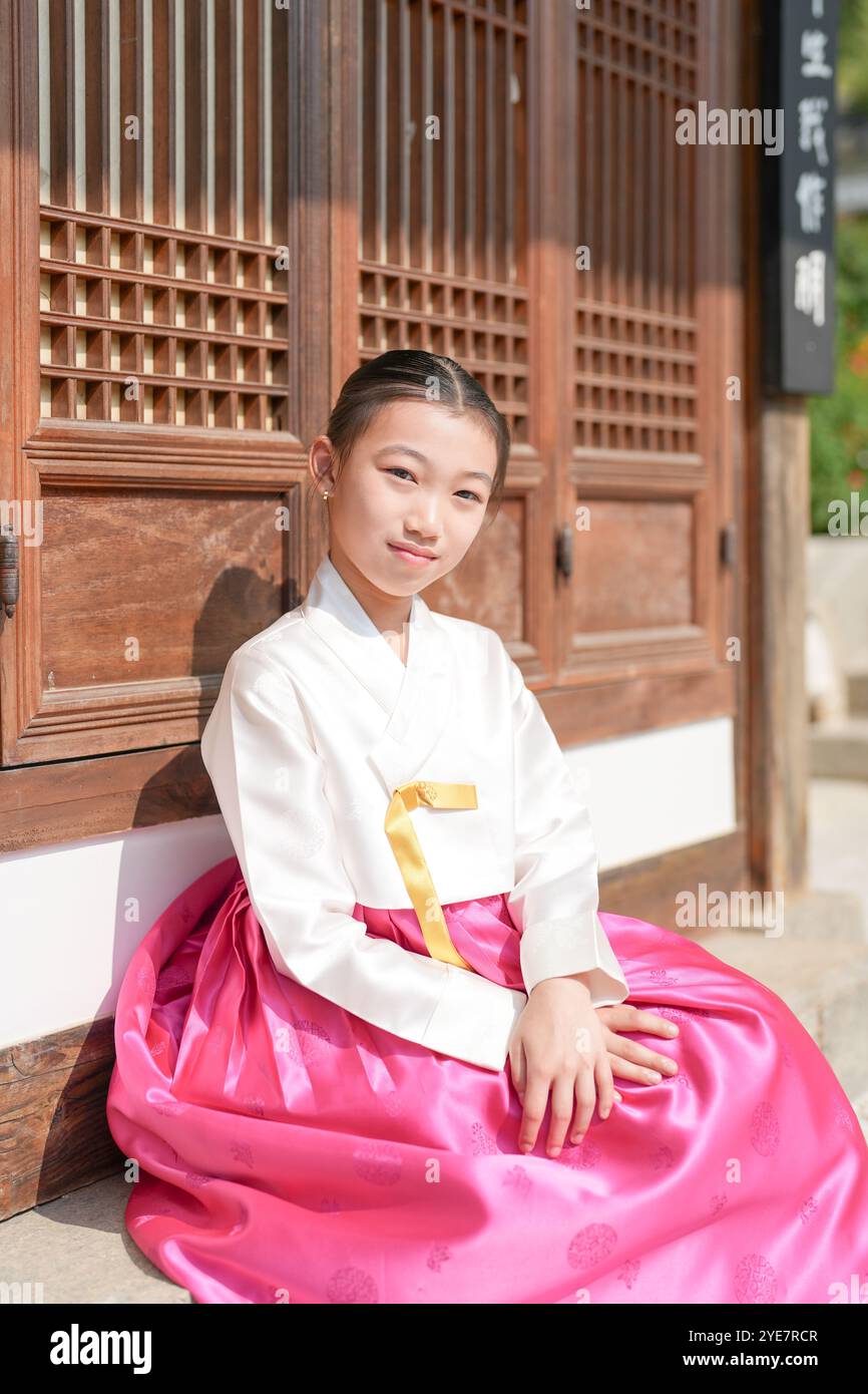 Une jeune coréenne de 9 ans portant un hanbok se tient debout devant un bâtiment traditionnel dans la ville historique de Gyedong-gil, district de Jongno, Séoul. Banque D'Images