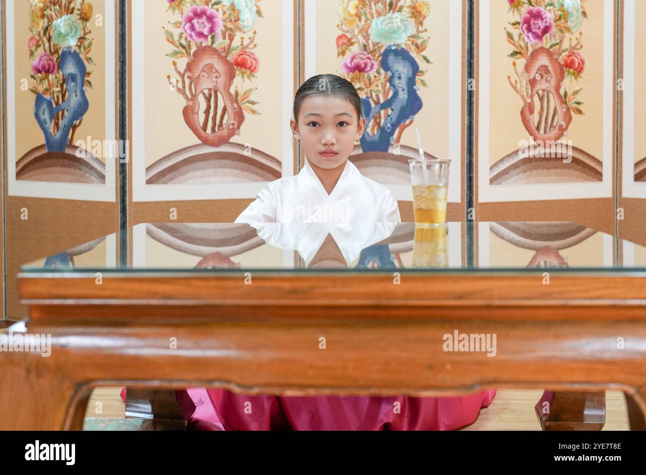 Une jeune coréenne de 9 ans portant un hanbok boit une boisson dans un bâtiment traditionnel de la ville historique de Gyedong-gil, dans le district de Jongno, au sud Banque D'Images