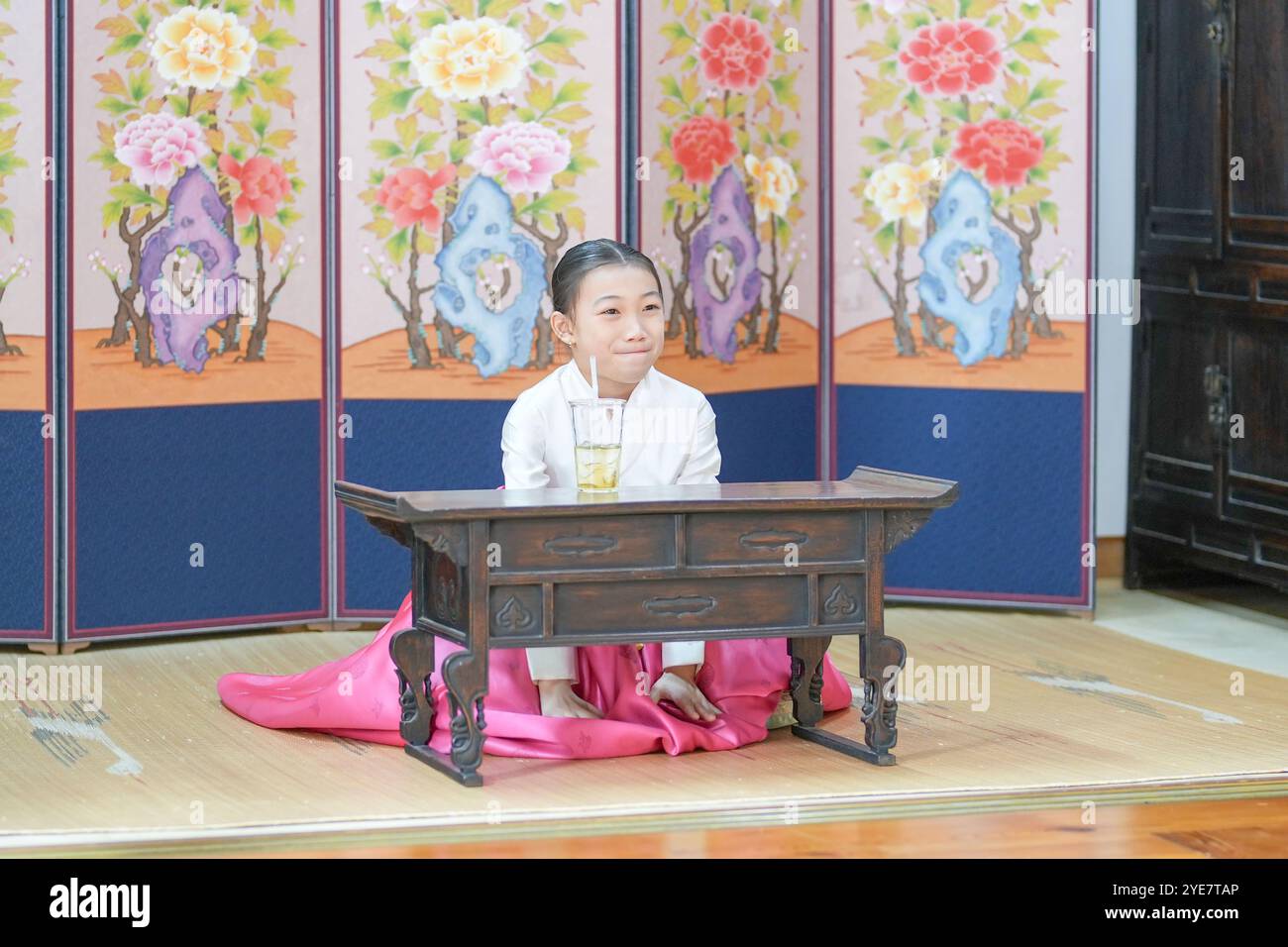 Une jeune coréenne de 9 ans portant un hanbok boit une boisson dans un bâtiment traditionnel de la ville historique de Gyedong-gil, dans le district de Jongno, au sud Banque D'Images
