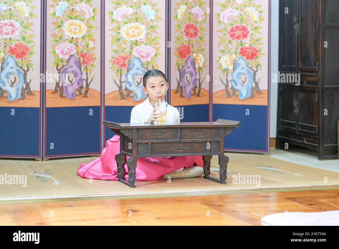 Une jeune coréenne de 9 ans portant un hanbok boit une boisson dans un bâtiment traditionnel de la ville historique de Gyedong-gil, dans le district de Jongno, au sud Banque D'Images