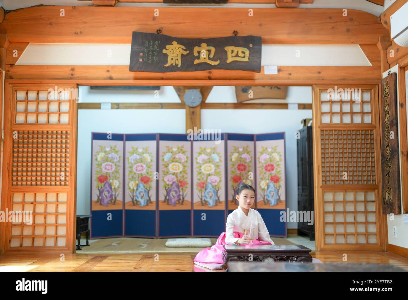 Une jeune coréenne de 9 ans portant un hanbok boit une boisson dans un bâtiment traditionnel de la ville historique de Gyedong-gil, dans le district de Jongno, au sud Banque D'Images