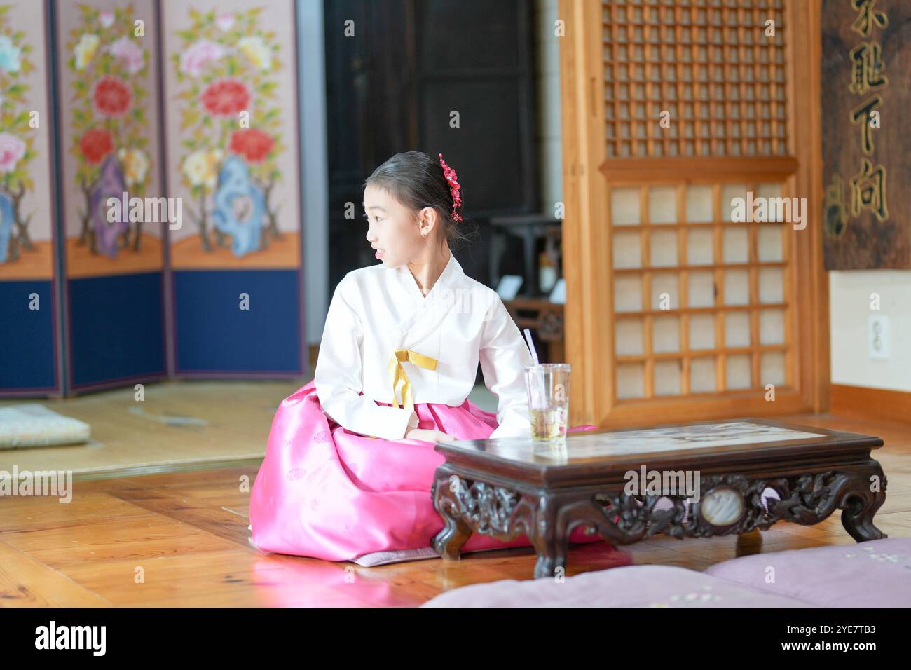 Une jeune coréenne de 9 ans portant un hanbok boit une boisson dans un bâtiment traditionnel de la ville historique de Gyedong-gil, dans le district de Jongno, au sud Banque D'Images