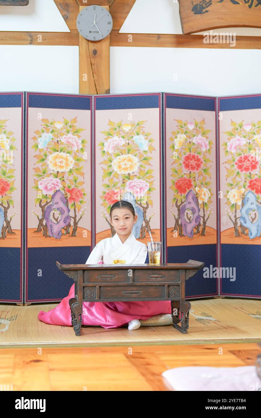 Une jeune coréenne de 9 ans portant un hanbok boit une boisson dans un bâtiment traditionnel de la ville historique de Gyedong-gil, dans le district de Jongno, au sud Banque D'Images