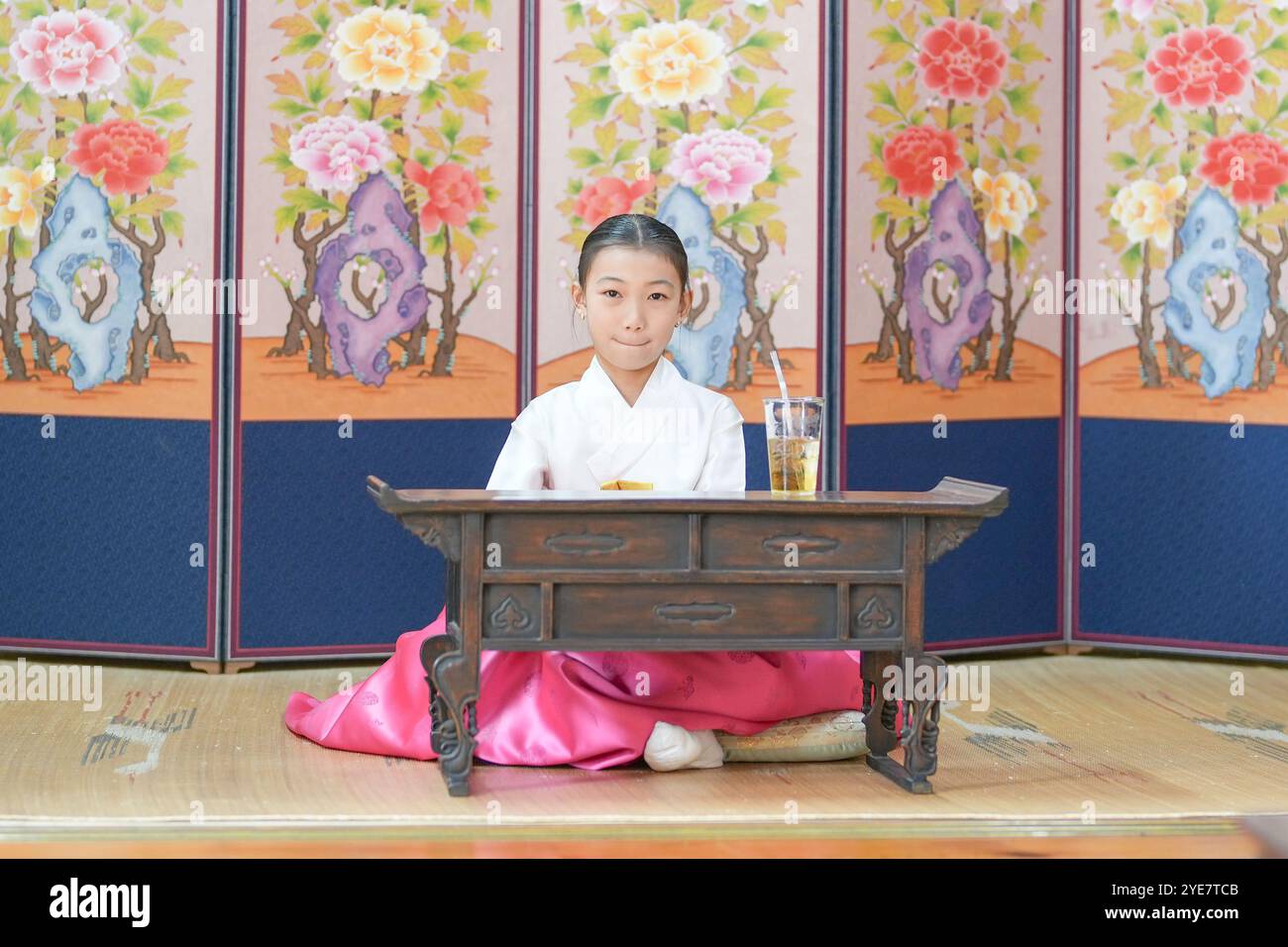 Une jeune coréenne de 9 ans portant un hanbok boit une boisson dans un bâtiment traditionnel de la ville historique de Gyedong-gil, dans le district de Jongno, au sud Banque D'Images