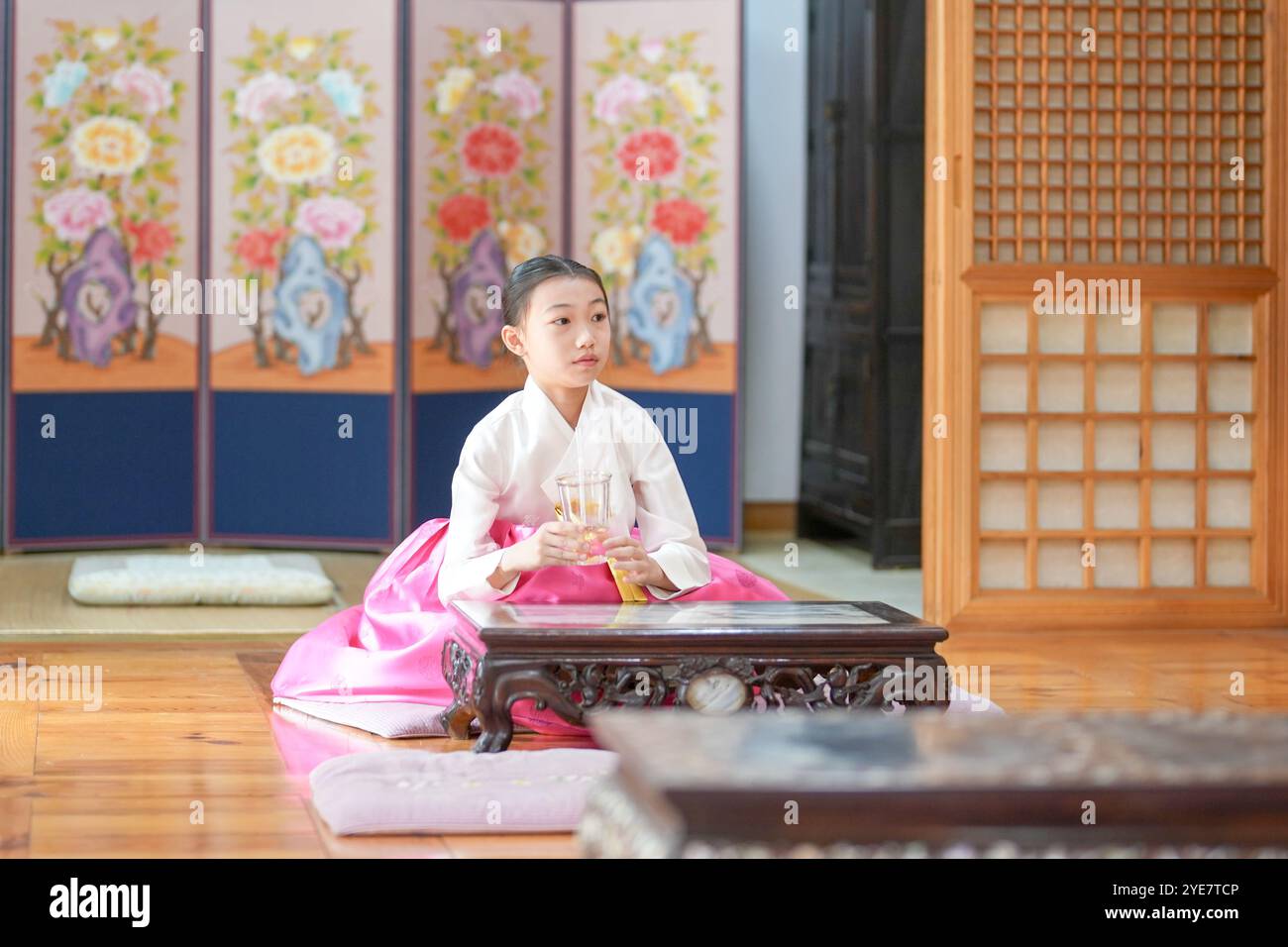 Une jeune coréenne de 9 ans portant un hanbok boit une boisson dans un bâtiment traditionnel de la ville historique de Gyedong-gil, dans le district de Jongno, au sud Banque D'Images