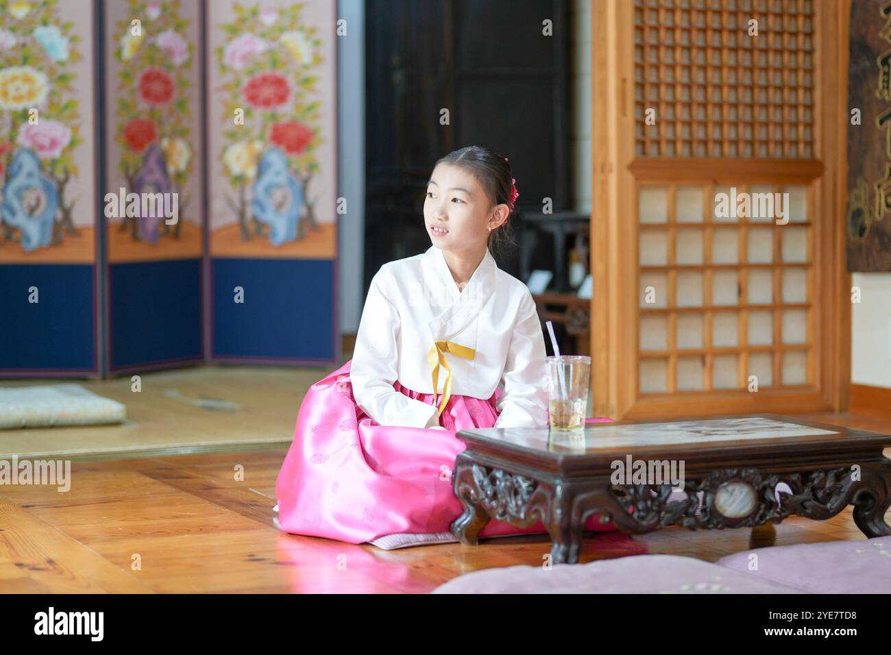 Une jeune coréenne de 9 ans portant un hanbok boit une boisson dans un bâtiment traditionnel de la ville historique de Gyedong-gil, dans le district de Jongno, au sud Banque D'Images