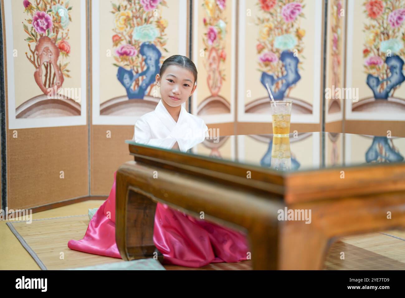 Une jeune coréenne de 9 ans portant un hanbok boit une boisson dans un bâtiment traditionnel de la ville historique de Gyedong-gil, dans le district de Jongno, au sud Banque D'Images