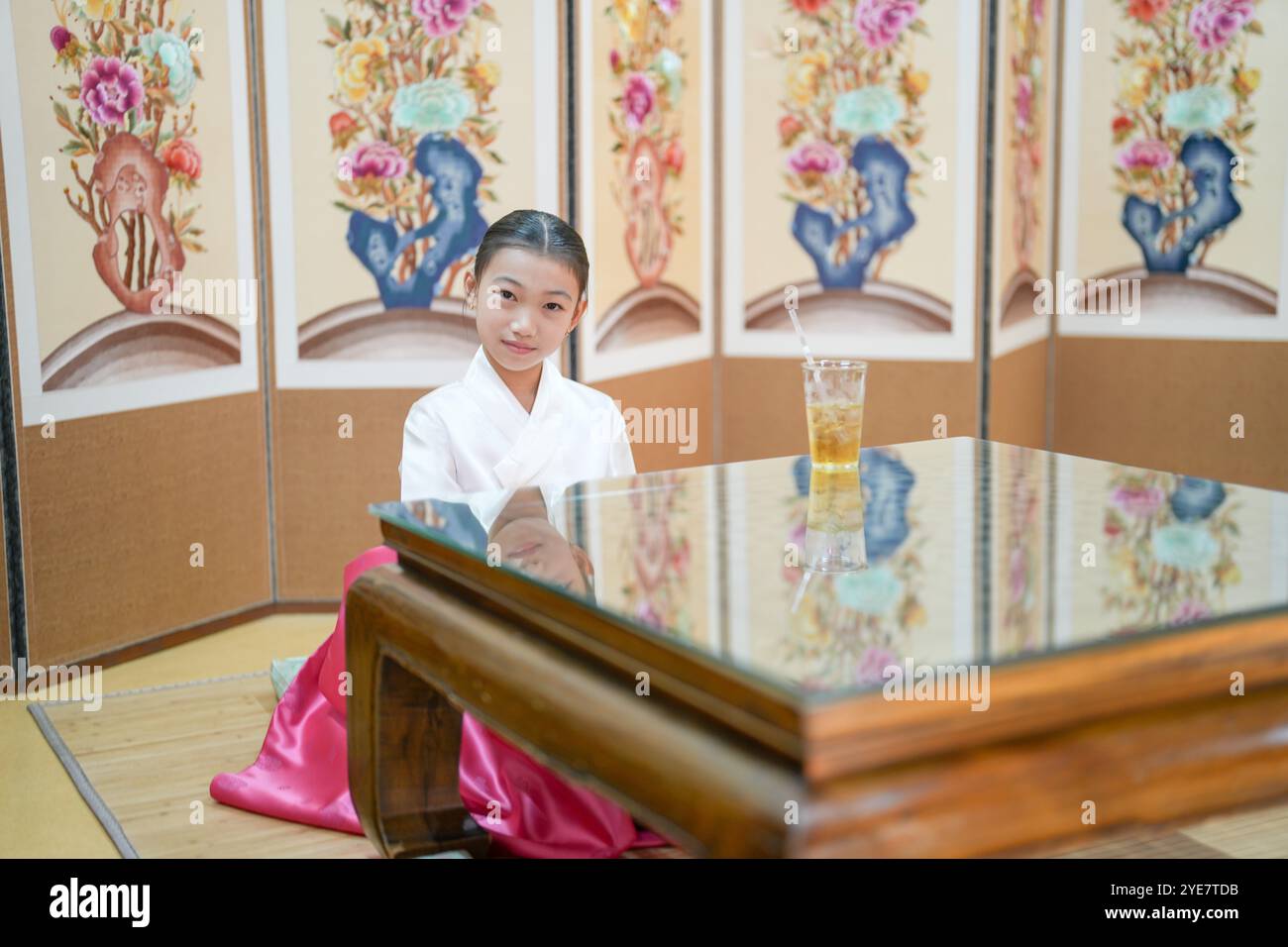 Une jeune coréenne de 9 ans portant un hanbok boit une boisson dans un bâtiment traditionnel de la ville historique de Gyedong-gil, dans le district de Jongno, au sud Banque D'Images