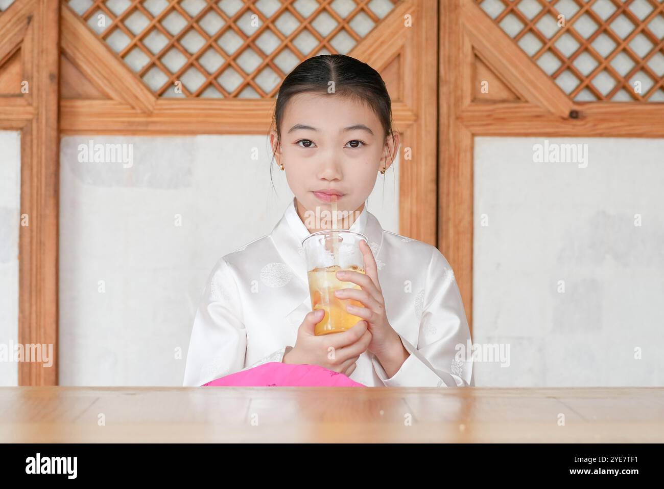 Une jeune coréenne de 9 ans portant un hanbok boit une boisson dans un bâtiment traditionnel de la ville historique de Gyedong-gil, dans le district de Jongno, au sud Banque D'Images