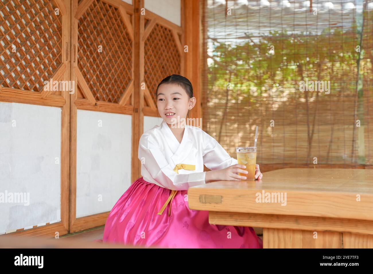 Une jeune coréenne de 9 ans portant un hanbok boit une boisson dans un bâtiment traditionnel de la ville historique de Gyedong-gil, dans le district de Jongno, au sud Banque D'Images