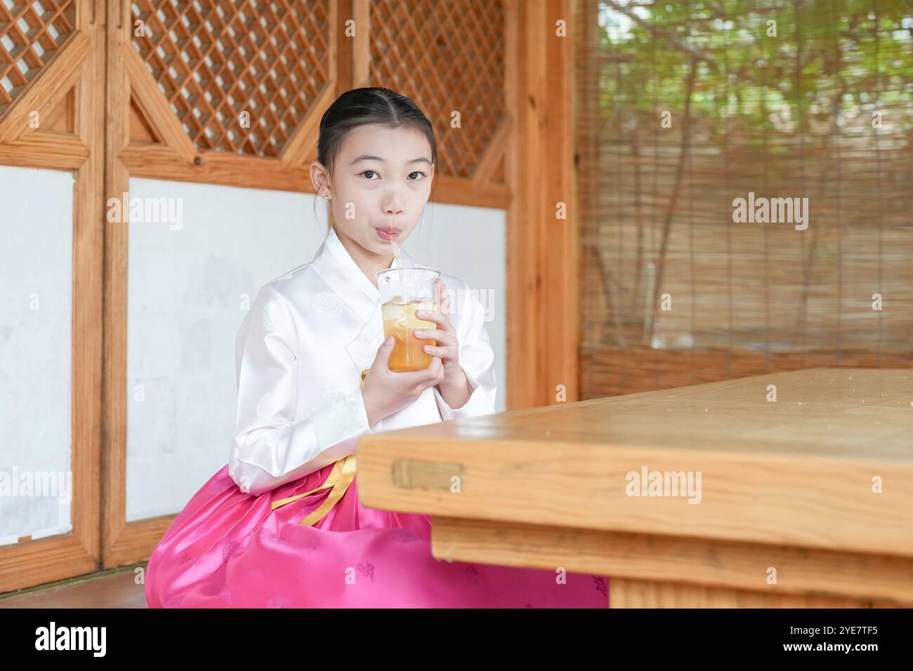 Une jeune coréenne de 9 ans portant un hanbok boit une boisson dans un bâtiment traditionnel de la ville historique de Gyedong-gil, dans le district de Jongno, au sud Banque D'Images