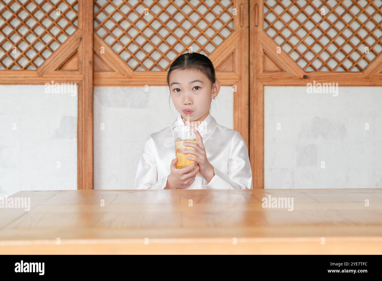 Une jeune coréenne de 9 ans portant un hanbok boit une boisson dans un bâtiment traditionnel de la ville historique de Gyedong-gil, dans le district de Jongno, au sud Banque D'Images