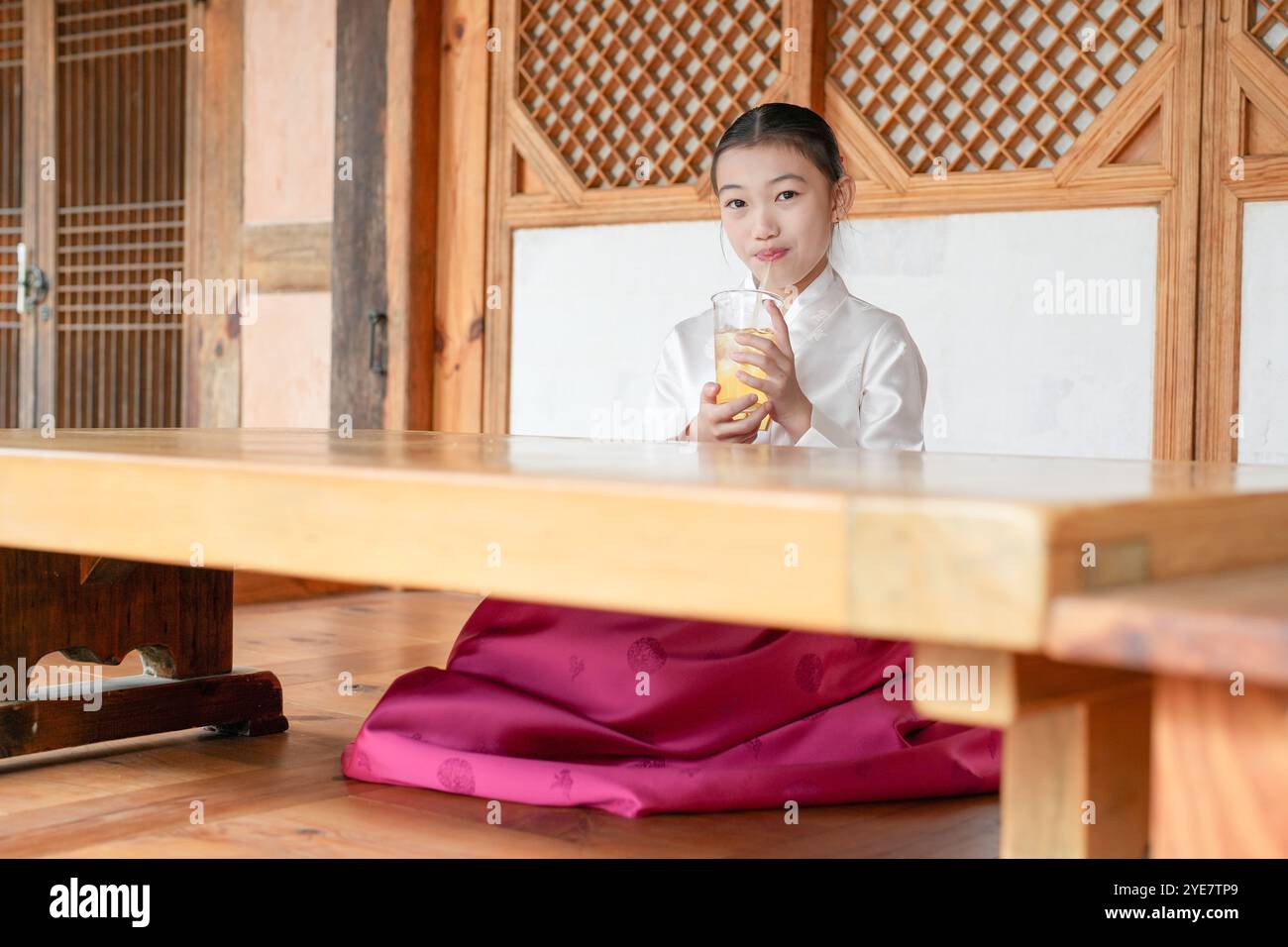 Une jeune coréenne de 9 ans portant un hanbok boit une boisson dans un bâtiment traditionnel de la ville historique de Gyedong-gil, dans le district de Jongno, au sud Banque D'Images