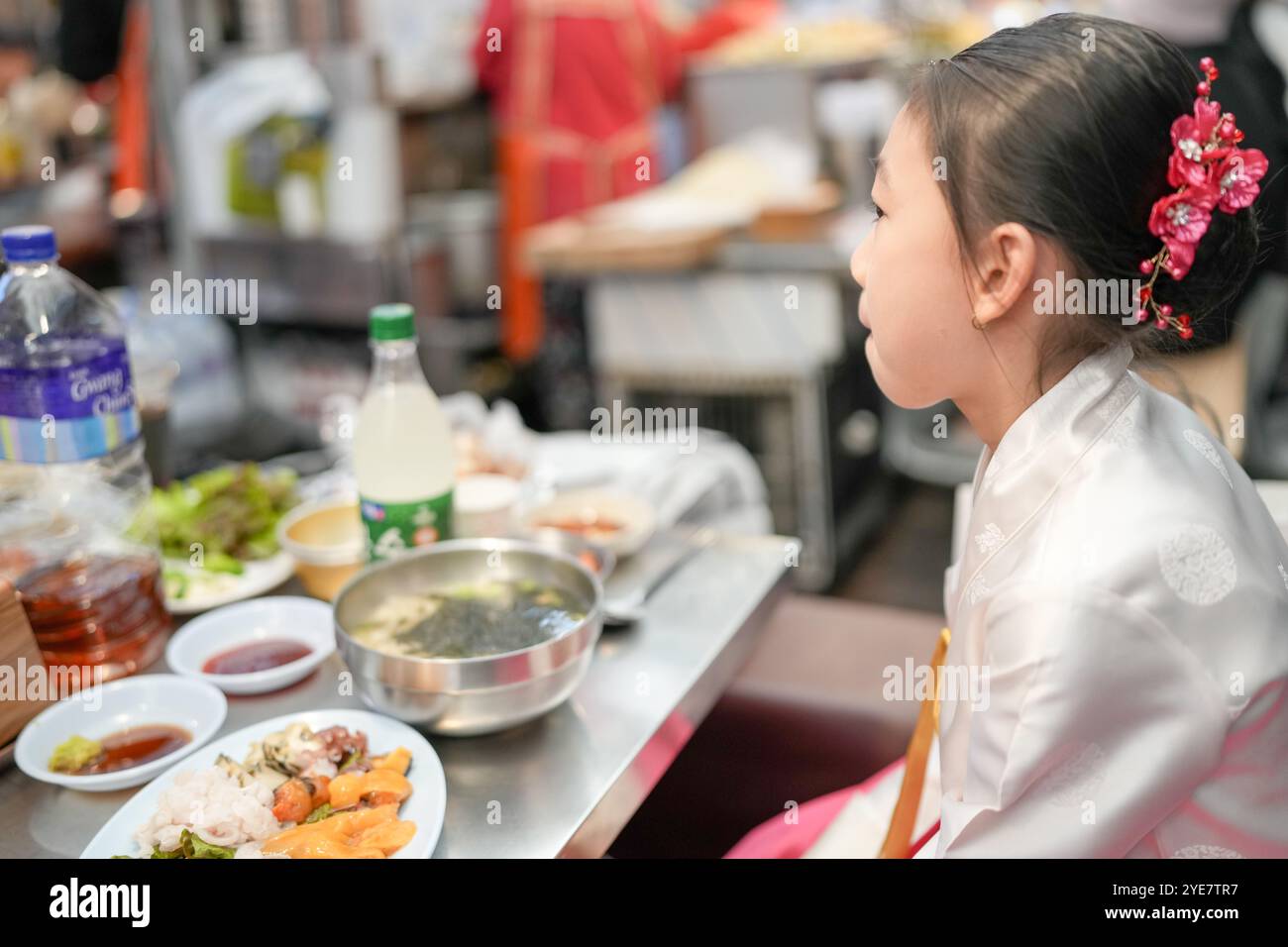Une jeune coréenne de 9 ans portant un hanbok mange un repas dans un marché local de Changgyeonggung-ro, district de Jongno, Séoul, Corée. Banque D'Images