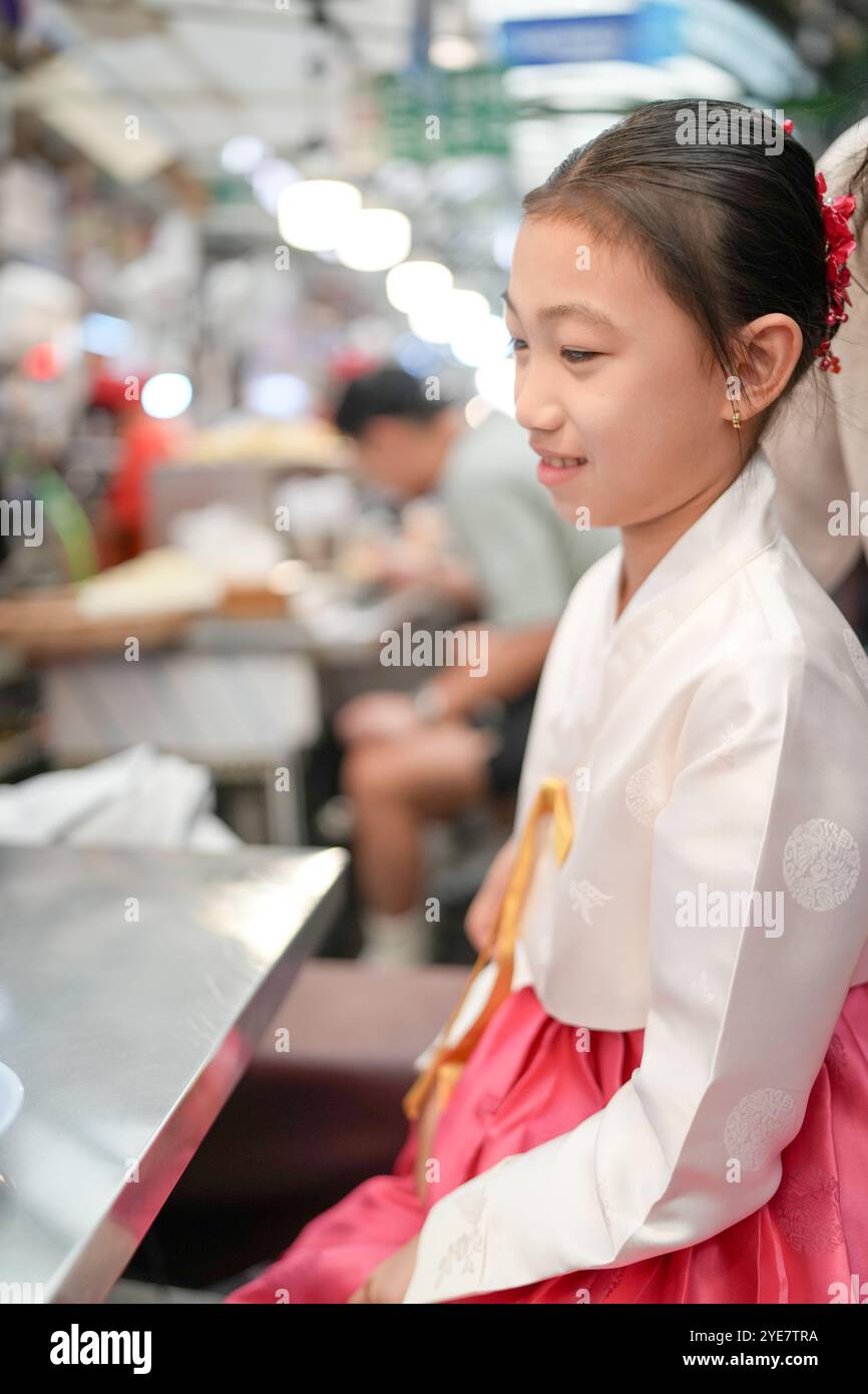 Une jeune coréenne de 9 ans portant un hanbok mange un repas dans un marché local de Changgyeonggung-ro, district de Jongno, Séoul, Corée. Banque D'Images