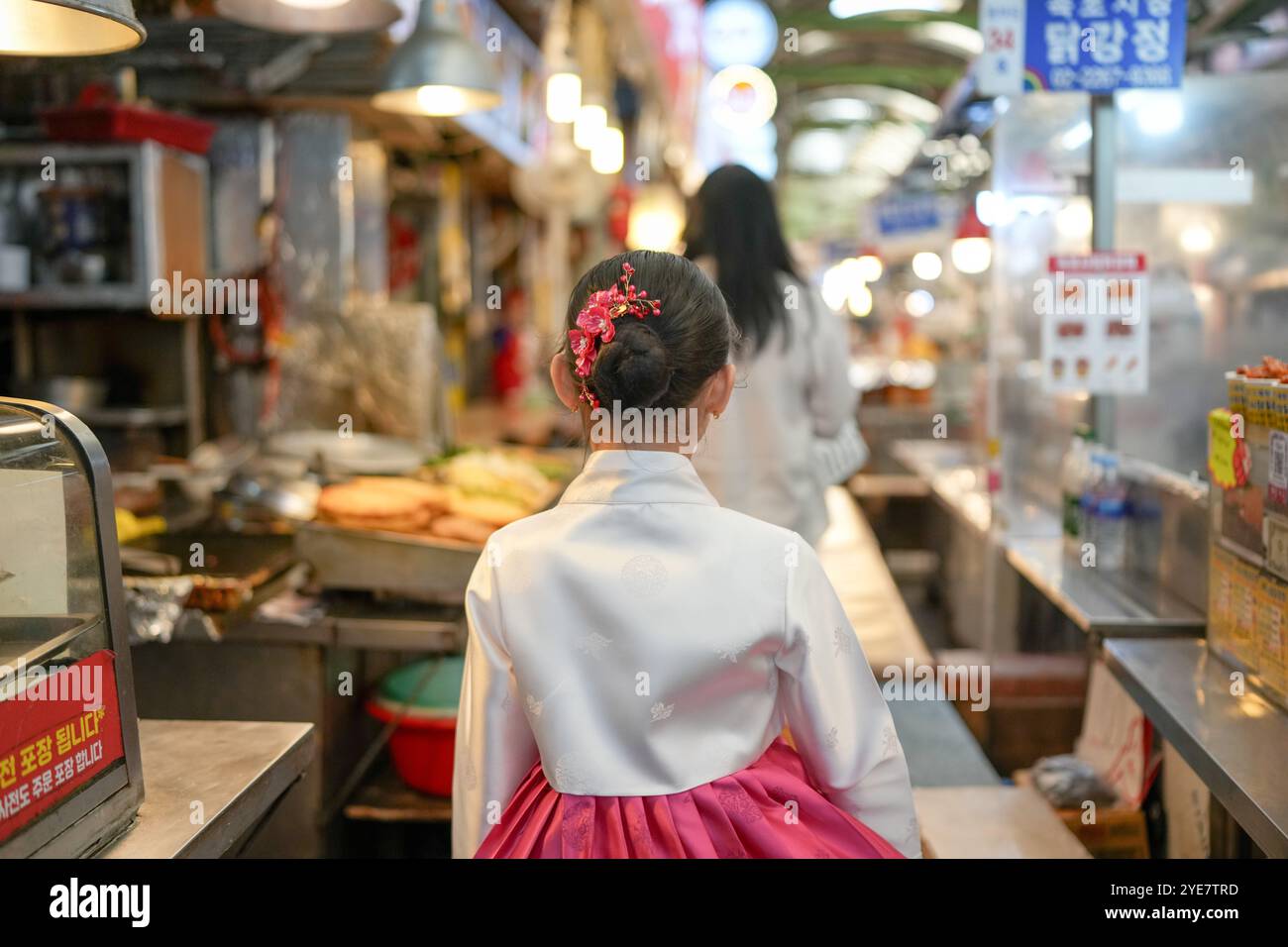 Une jeune coréenne de 9 ans portant un hanbok mange un repas dans un marché local de Changgyeonggung-ro, district de Jongno, Séoul, Corée. Banque D'Images