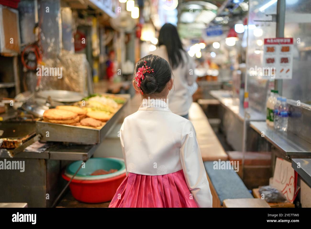 Une jeune coréenne de 9 ans portant un hanbok mange un repas dans un marché local de Changgyeonggung-ro, district de Jongno, Séoul, Corée. Banque D'Images