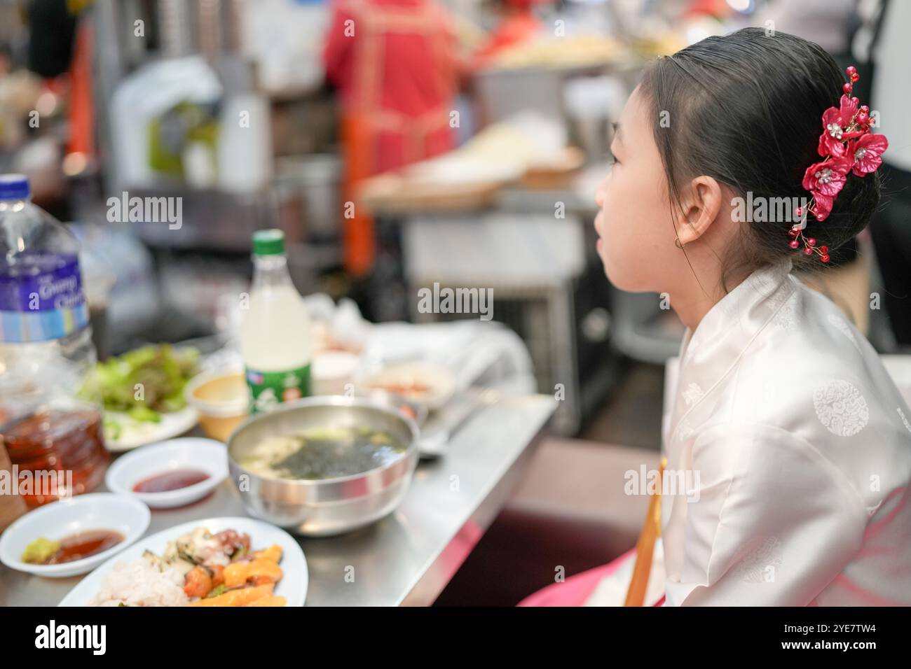 Une jeune coréenne de 9 ans portant un hanbok mange un repas dans un marché local de Changgyeonggung-ro, district de Jongno, Séoul, Corée. Banque D'Images
