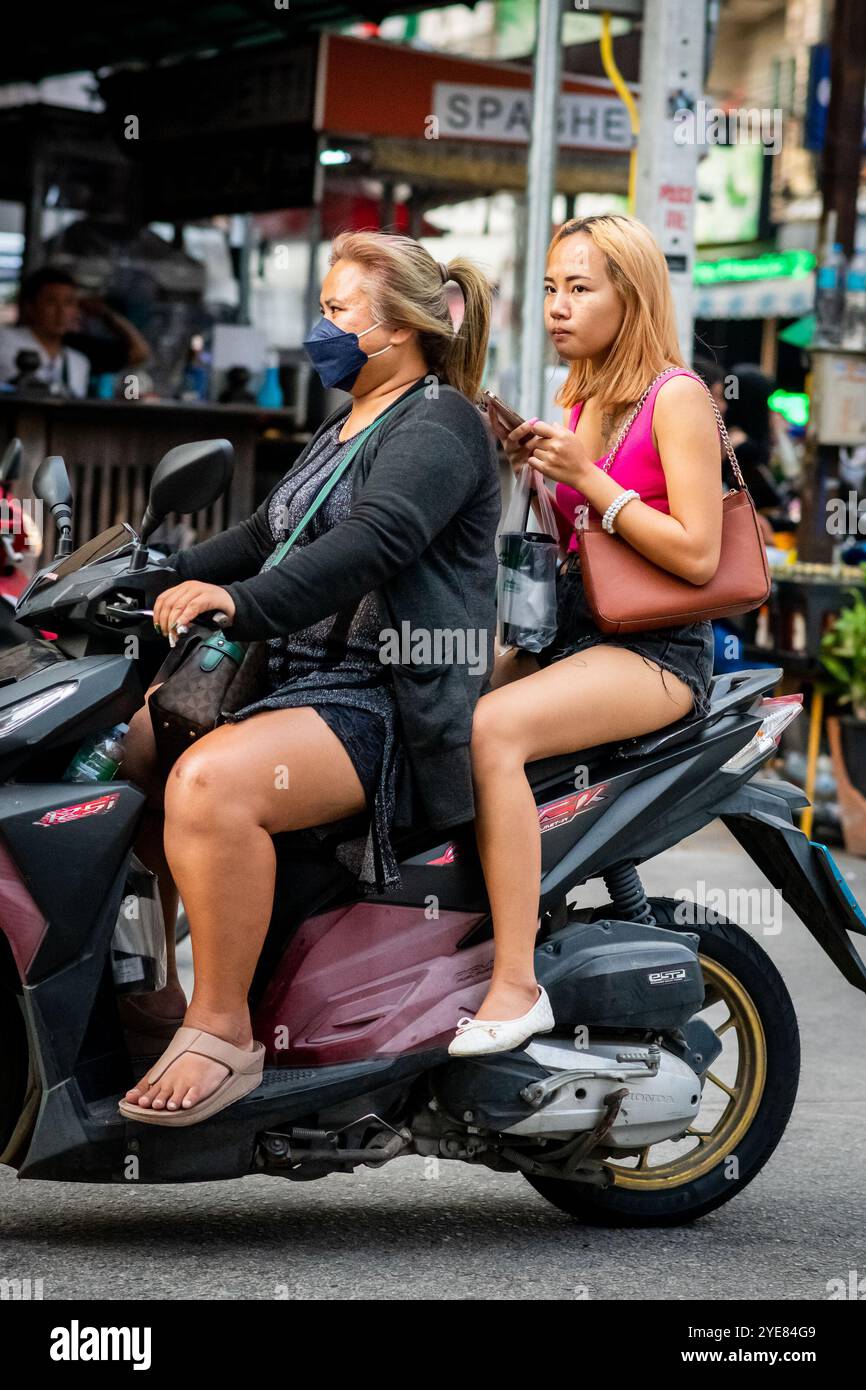 Deux filles thaïlandaises font leur chemin le long de soi Buakhao, Pattaya, Thaïlande sur leur scooter. Banque D'Images