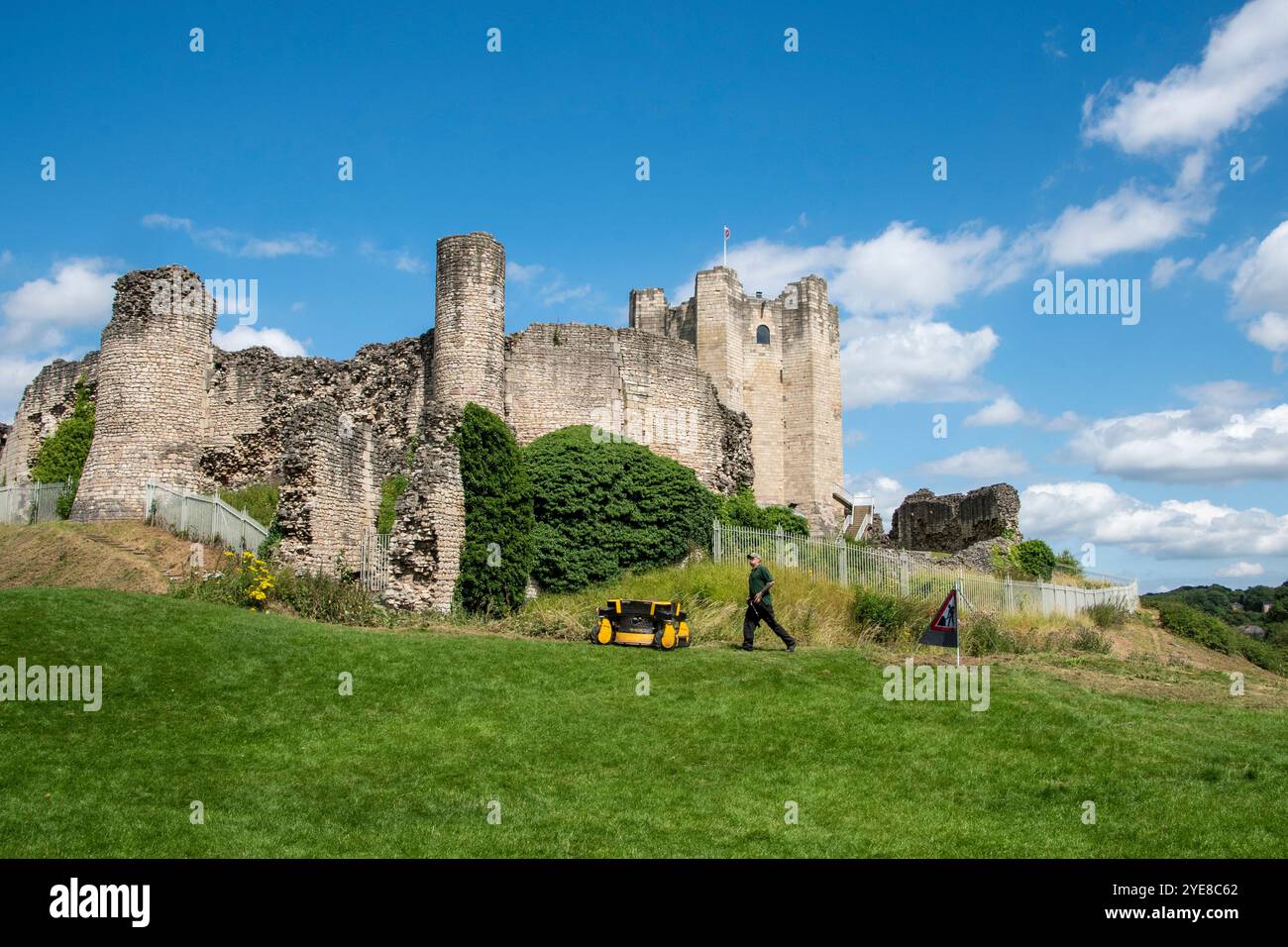 Yorkshire, Royaume-Uni – 23 juillet 2024 : un jardinier tond l'herbe devant le château de Conisbrough, une fortification médiévale du XIIe siècle Banque D'Images