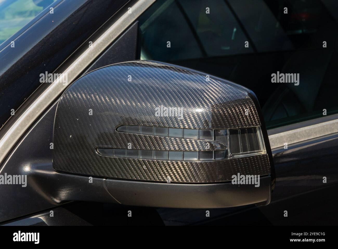 Une vue avant détaillée d'un rétroviseur noir recouvert de carbone dans une voiture, soulignant son design élégant et ses éraflures subtiles pour une automobile authentique Banque D'Images