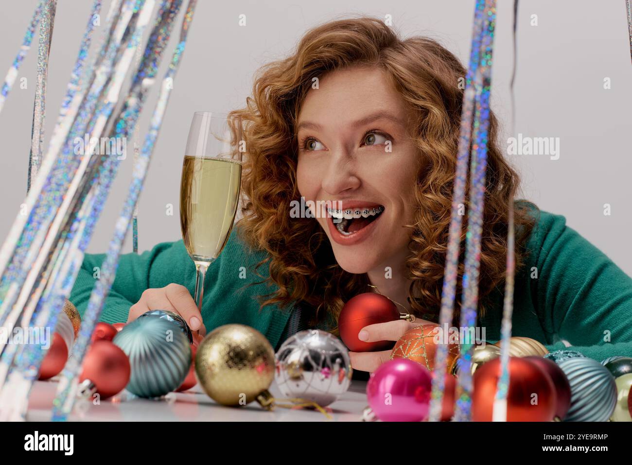 Une jeune femme aime l'esprit festif, posant joyeusement et entourée de décorations colorées. Banque D'Images