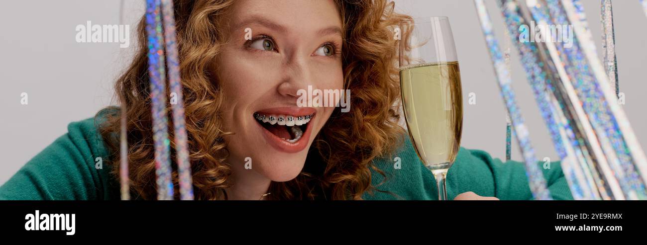 Une jeune femme prépare avec enthousiasme des cadeaux au milieu de décorations festives et de boissons pétillantes. Banque D'Images