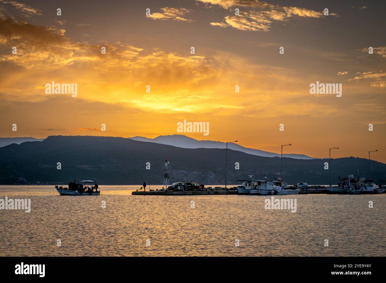 Un petit bateau de pêche quittant le port, se dirigeant vers la mer le matin avec un beau lever de soleil doré. Banque D'Images