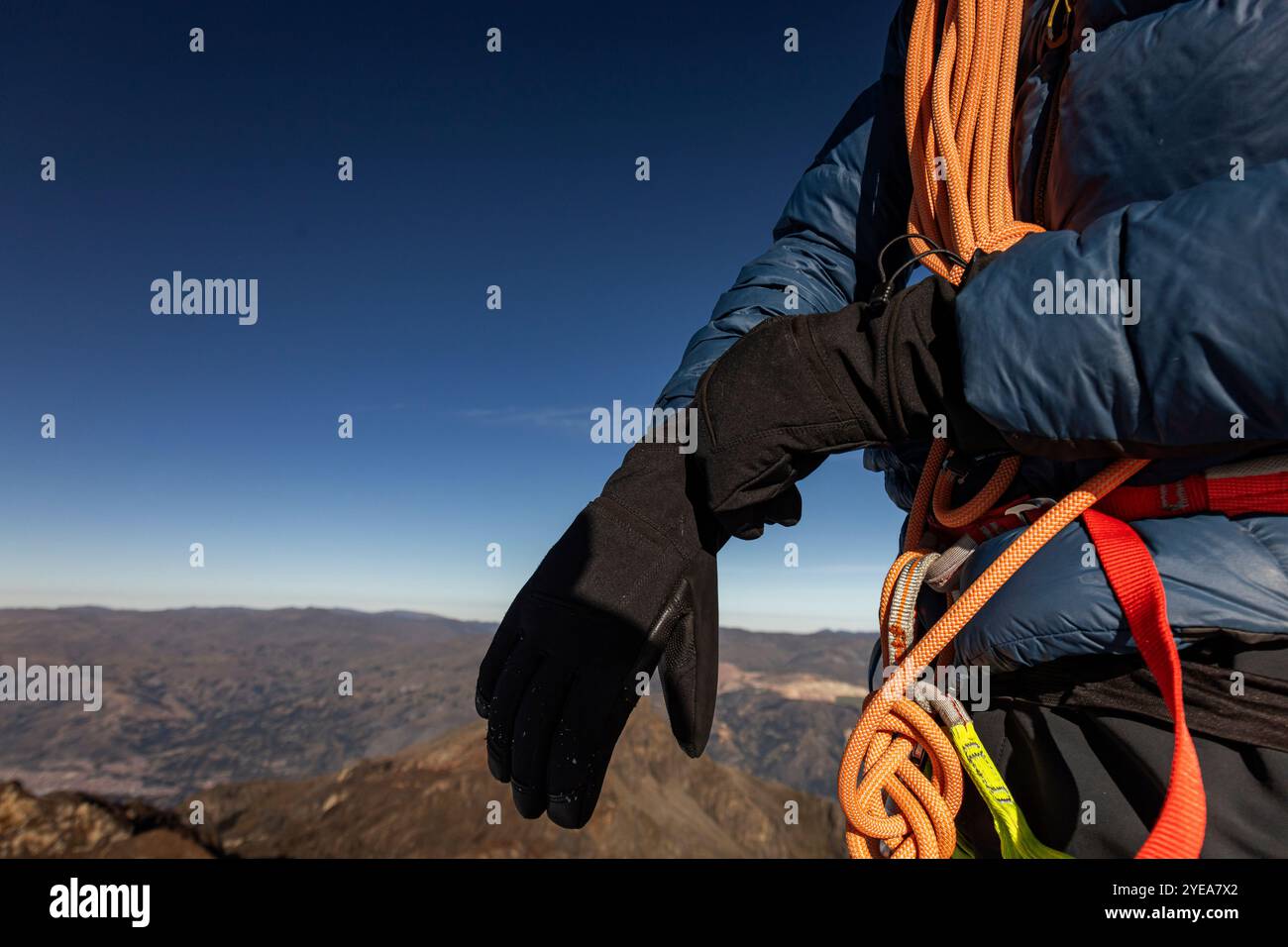 Mains de l'homme ajustant ses gants, équipement d'escalade de neige, vis, mousqueton, corde Banque D'Images