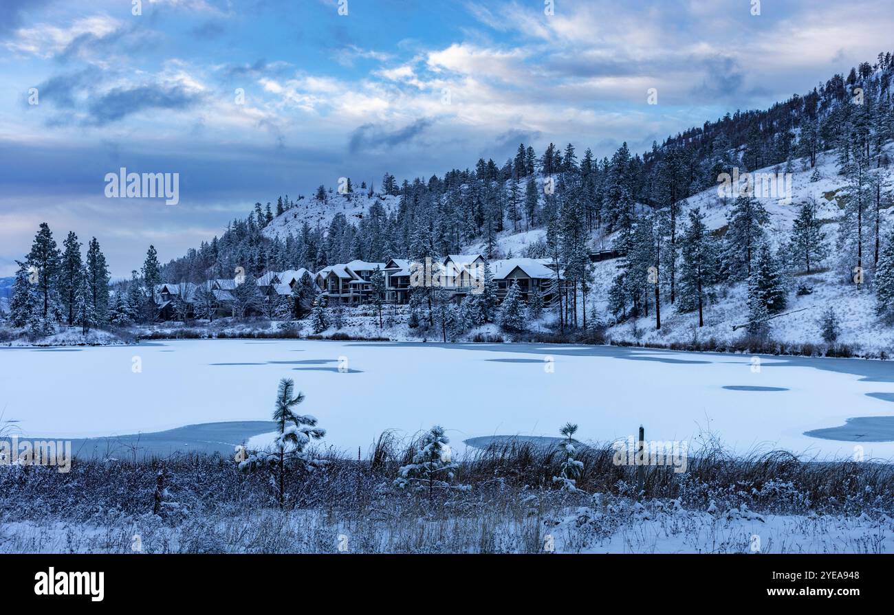 Développement de logements par un lac gelé enneigé en hiver ; Kelowna, Colombie-Britannique, Canada Banque D'Images