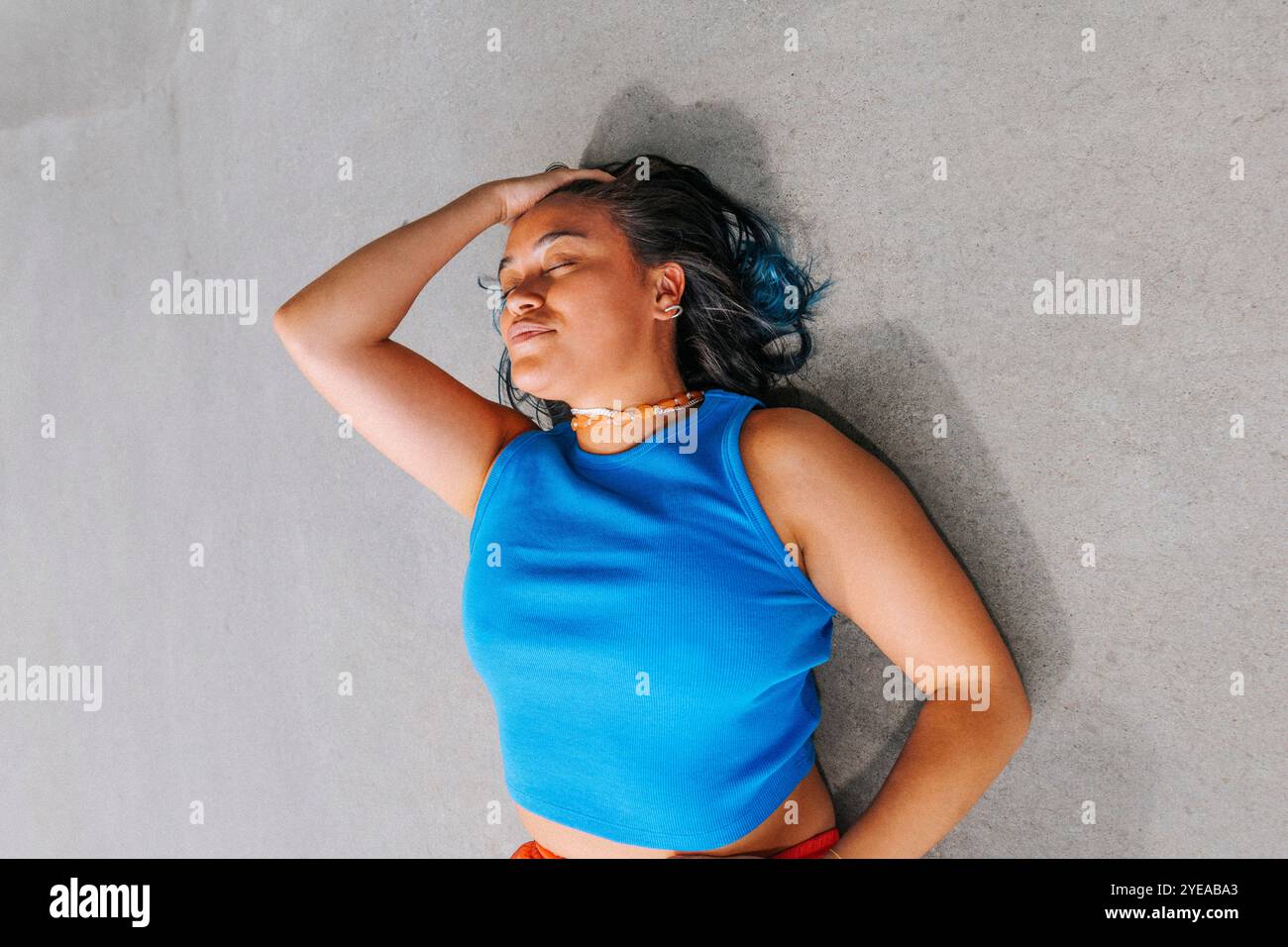 Vue en angle élevé de la jeune femme avec la main dans les cheveux couchés sur le sol Banque D'Images