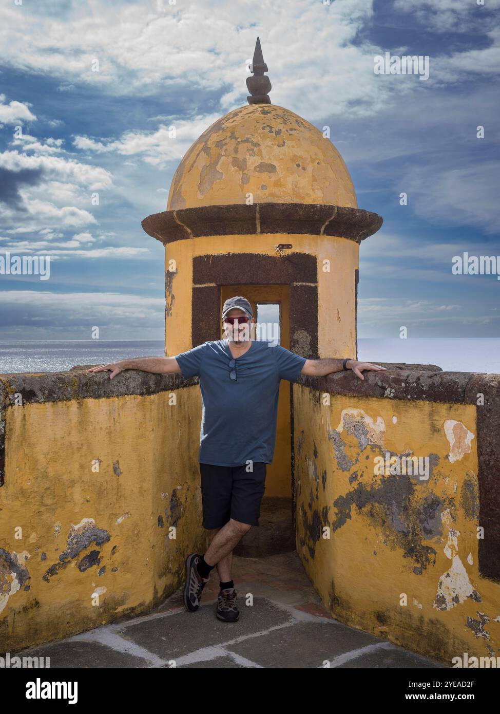Stands de touristes masculins posant à une tour de guet altérée et mur de pierre au bord de l'eau Fort de Sao Tiago dans la ville côtière de Funchal sur l'île... Banque D'Images