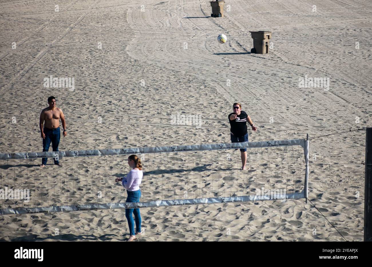Joueurs de Beach volley informels appréciant la journée en regardant les gens avec le ballon en jeu sur le sable Banque D'Images